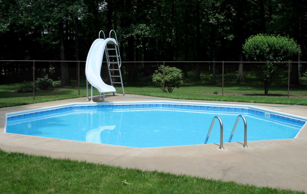 swimming pool and slide enclosed in a fenced-in area - Whats a Safe Pool Depth for a Slide