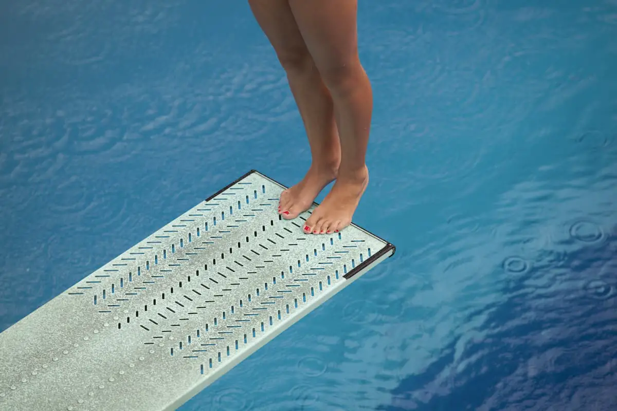 Girl standing on diving board getting ready to spring into the water